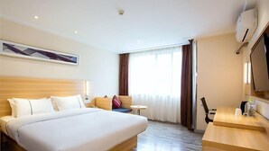 A hotel room with a large bed, a desk, a chair, a small table, a sofa, and a TV. - City Comfort Inn (Guilin)