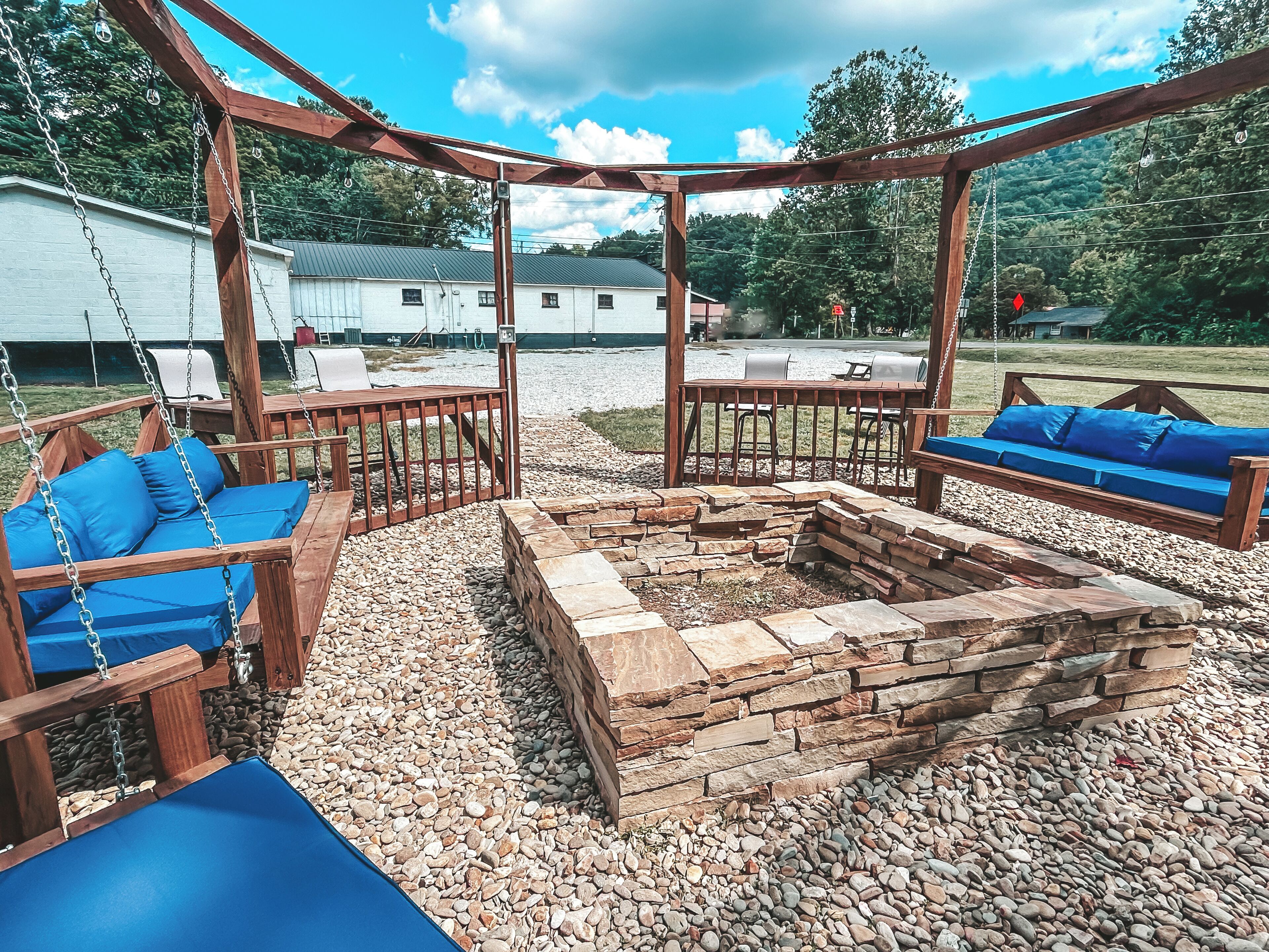A wooden pergola with a fire pit and seating area.