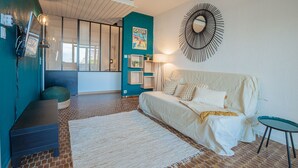 Une chambre à coucher moderne avec un sol en briques, un lit blanc, un mur bleu et un miroir décoratif.