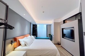 A modern hotel room with a large bed, a TV mounted on the wall, and a view of the city through the window.