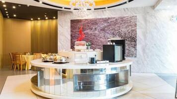 A hotel reception area with a circular counter, a marble wall, and a chandelier.