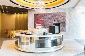 Uma área de recepção de hotel com um balcão circular, uma parede de mármore e um candelabro.