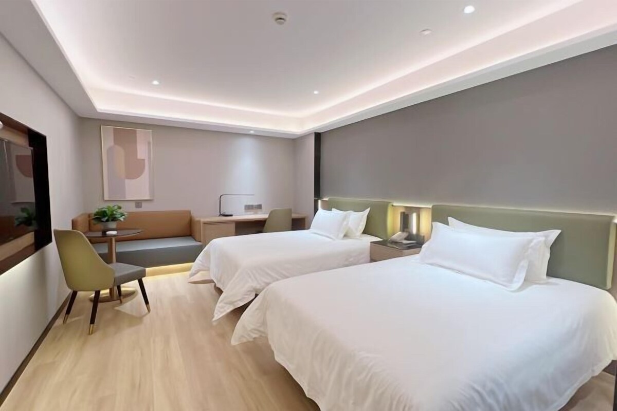 Una camera d'albergo moderna con due letti singoli, una scrivania, una sedia e un divano.