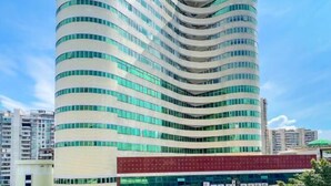 Un grand hôtel aux lignes courbes, doté de nombreux balcons et caractérisé par une partie rouge bien visible à sa base.