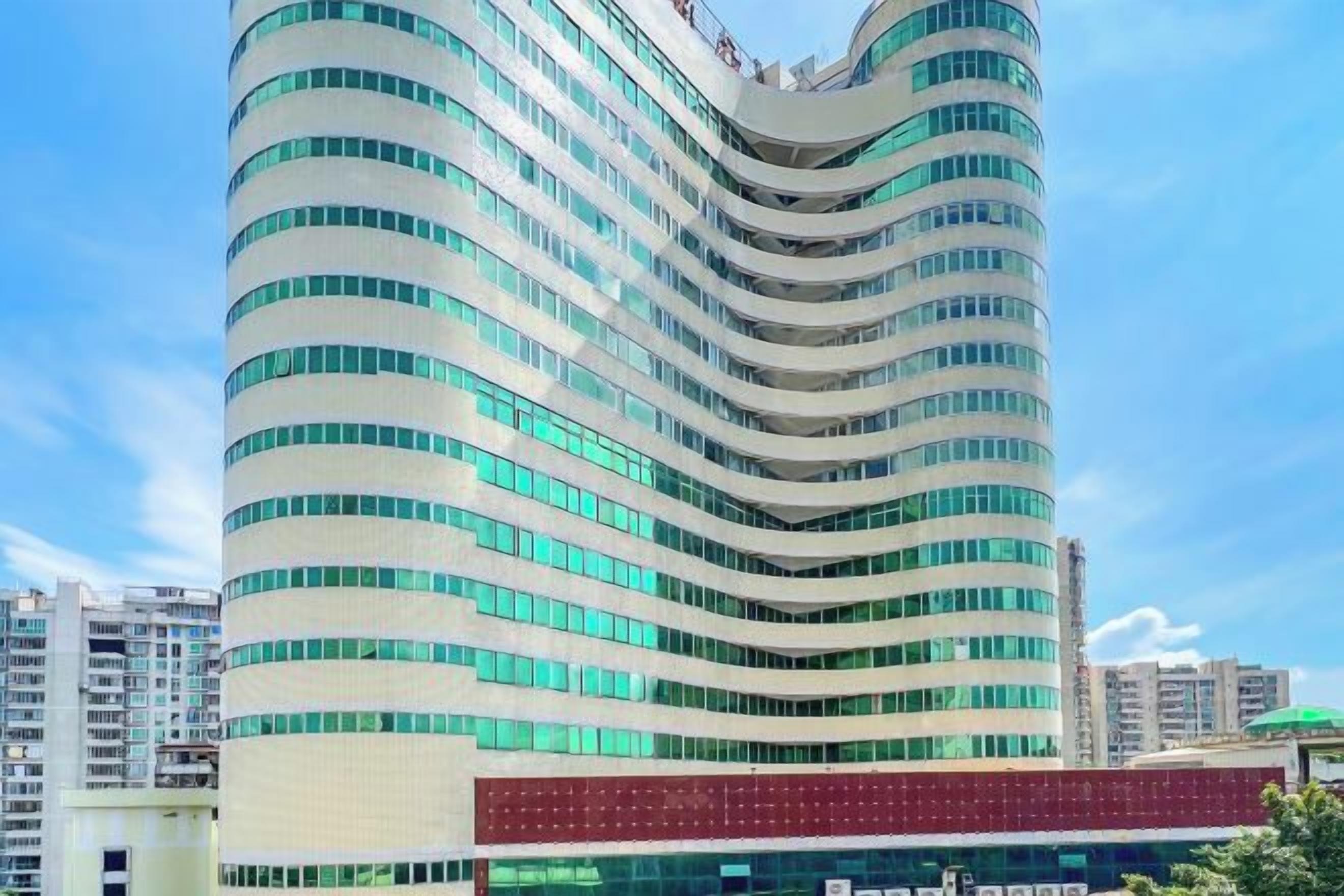 Een modern hotel met een gebogen gevel, meerdere verdiepingen en een opvallende rode ingang.