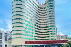 A modern hotel with a curved facade, multiple floors, and a prominent red entrance. - Nanan Hotel (Nan'an)