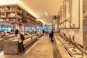 A modern hotel lobby with a long reception desk, a buffet area, and a seating area with tables and chairs. - Nanan Hotel (Nan'an)