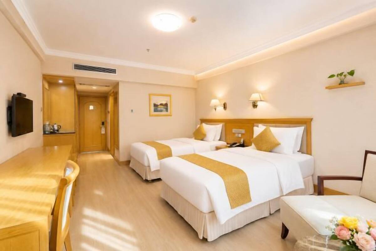 A hotel room with two beds, a desk, and a chair.