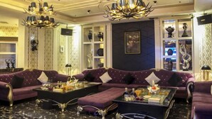 Un salon luxueux avec un grand canapé d’angle, une table basse en verre et deux lustres.