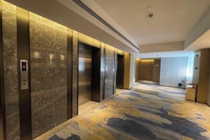 A hotel corridor with elevators and a patterned carpet. - Nanan Hotel (Nan'an)