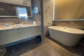 A modern bathroom with a large freestanding bathtub, a vanity with a mirror, and a shower area.