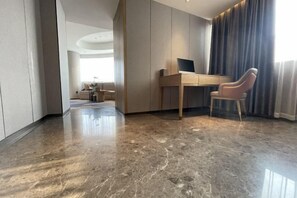 Une chambre d’hôtel moderne avec un sol en marbre, un bureau équipé d’un ordinateur et une chaise.