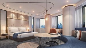 Une chambre d’hôtel moderne avec un lit, une table ronde, un canapé et une vue sur la ville.