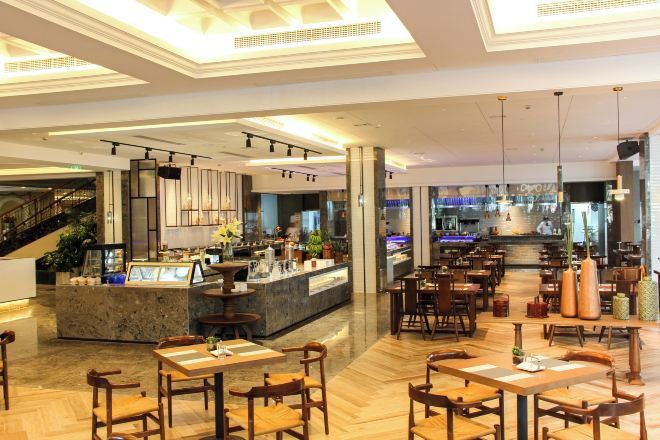Een ruime hotelentree met een bar in het midden, diverse zithoeken en een trap naar de bovenverdiepingen.