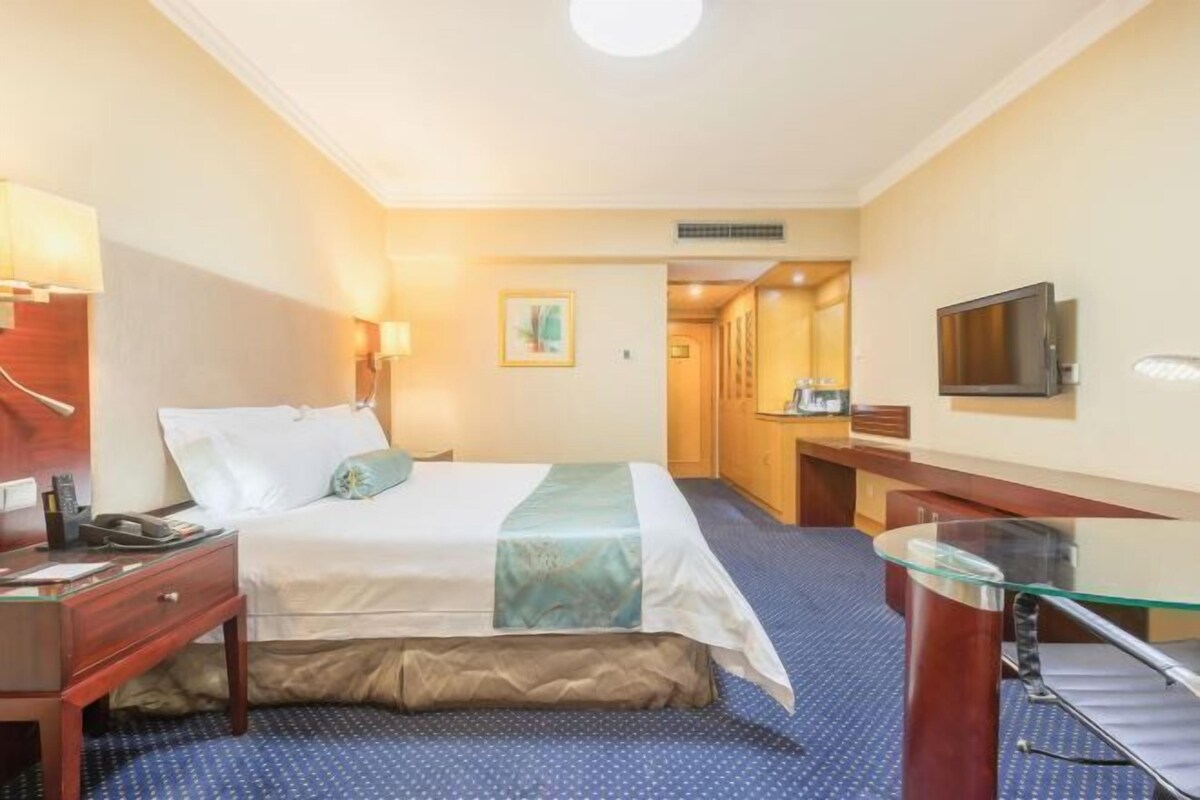 Une chambre d’hôtel comprenant un lit, une table de chevet, une lampe, une télévision et un bureau.