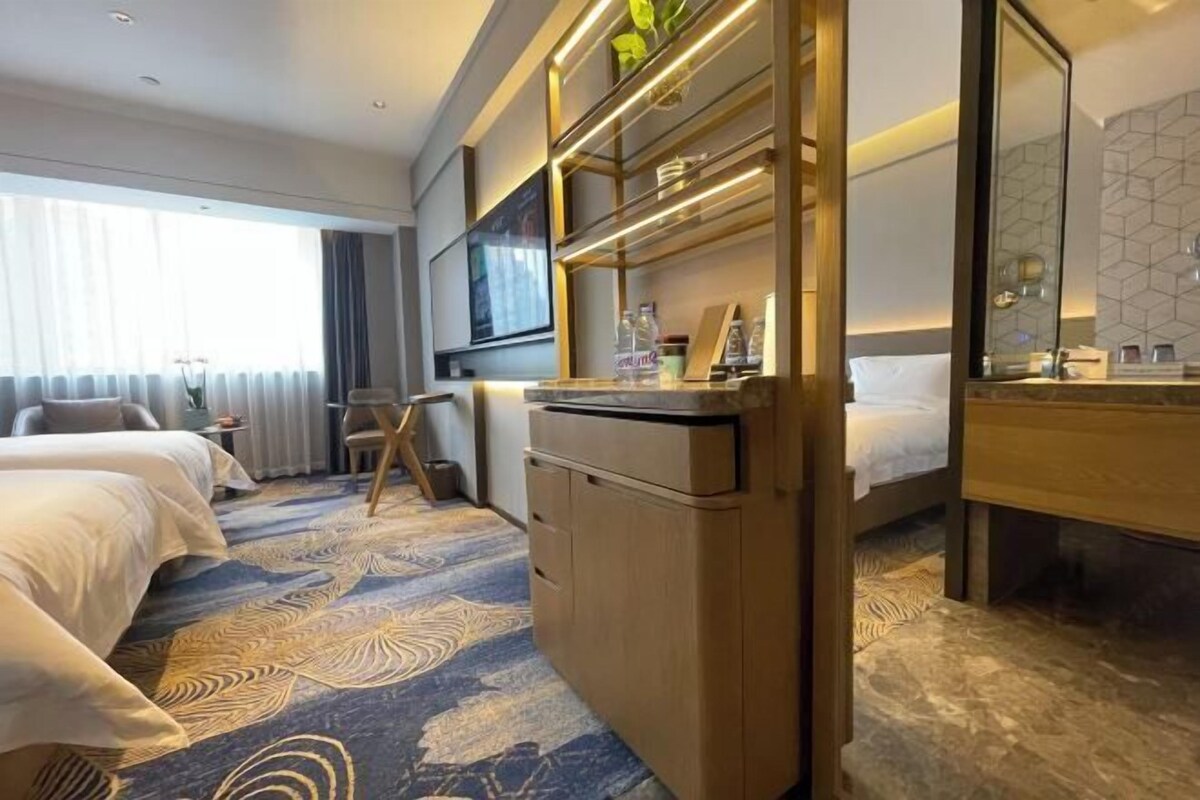 Une chambre d’hôtel avec un lit, un bureau, une chaise, une télévision et une grande fenêtre.
