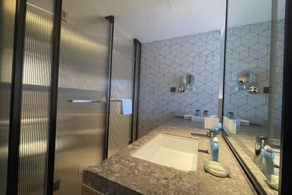 Une salle de bain moderne avec un grand miroir, un lavabo et un espace douche.