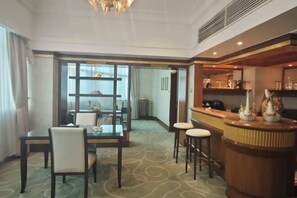 Une chambre d’hôtel avec un coin repas, un bar et une vue sur l’extérieur, accessible par une porte vitrée.