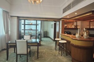 Habitación de hotel con comedor, bar y vista por un ventanal.