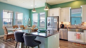A modern kitchen with a central island, white cabinets, and a teal accent wall.