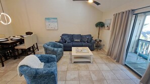 Ein Wohnzimmer mit einer Couch, zwei Sesseln, einem Couchtisch und einem Essbereich mit Tisch und Stühlen.