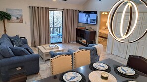 A living room with a television, a dining table with plates, and a large mirror. - Gulf Getaway #304 Free Beach Svc Chateau La Mer II 2nd Fl (Destin)