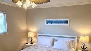 A bedroom with a white bed, two bedside lamps, a ceiling fan, a painting on the wall, and a patterned rug. - Gulf Getaway #304 Free Beach Svc Chateau La Mer II 2nd Fl (Destin)