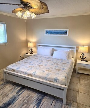 A bedroom with a white bed, two bedside lamps, a ceiling fan, a painting on the wall, and a patterned rug. - Gulf Getaway #304 Free Beach Svc Chateau La Mer II 2nd Fl (Destin)