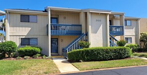 A two-story apartment building with a blue balcony on the second floor, a visible entrance, and a number '300' on the facade. - Gulf Getaway #304 Free Beach Svc Chateau La Mer II 2nd Fl (Destin)