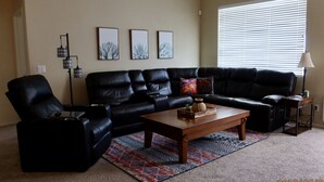 A living room with a sectional sofa, a coffee table, and a floor lamp. - Relax with Sonoran Nature Preserve views plus bike trails & several golf courses (Marana)
