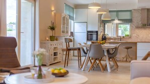 A modern kitchen with white cabinets, a dining area with a round table, and a bar area with stools. - Villa Lirica with Pool (Svetvinčenat)
