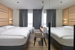 A hotel room with two beds, a small table, and a chair.