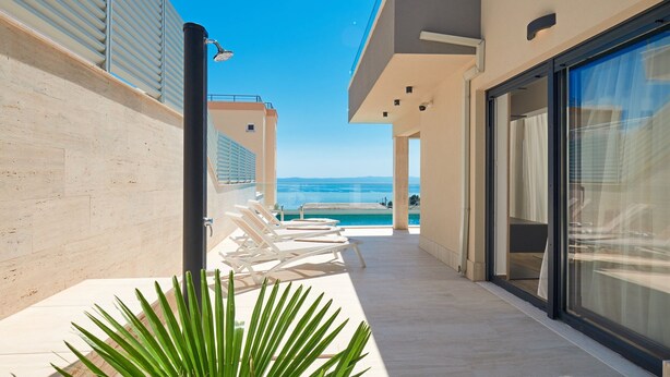 A corridor with a pool, lounge chairs, and a view of the sea. - Belmare Villas Complex (Makarska)