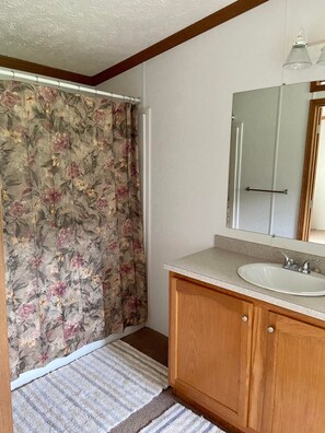 Een bad/douchecombinatie, handdoeken, zeep, toiletpapier