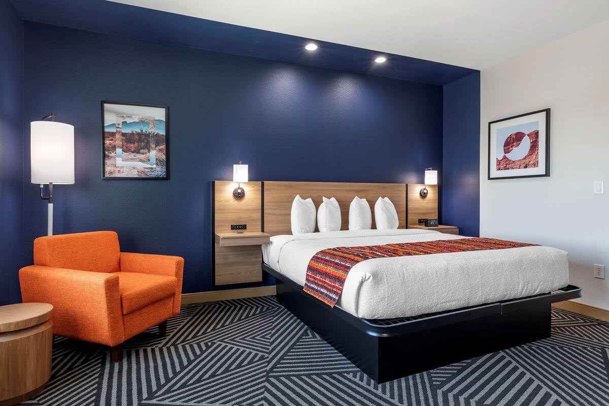 Een moderne hotelkamer met een groot bed, een nachtkastje, een stoel en twee wandlampen.