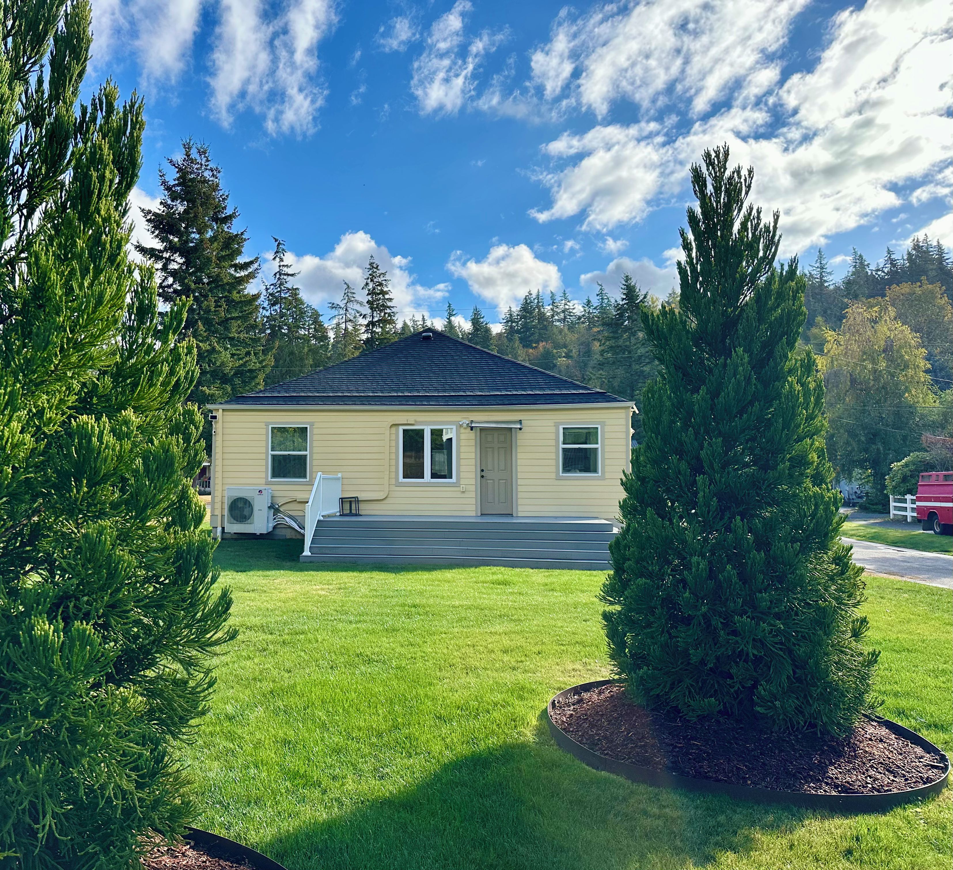 Une maison de plain-pied avec un porche à l’avant, un petit garage attenant et une pelouse bien entretenue.