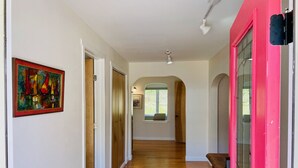 A hallway with wooden flooring, a pink door, and a framed painting on the wall. - Cottage of Tranquility (Bellingham)
