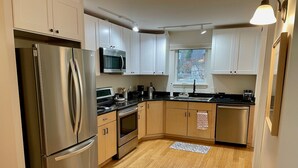 A modern kitchen with stainless steel appliances, wooden cabinets, and a black countertop. - Cottage of Tranquility (Bellingham)
