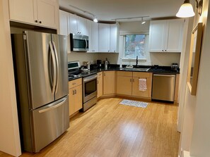 A modern kitchen with stainless steel appliances, wooden cabinets, and a black countertop.