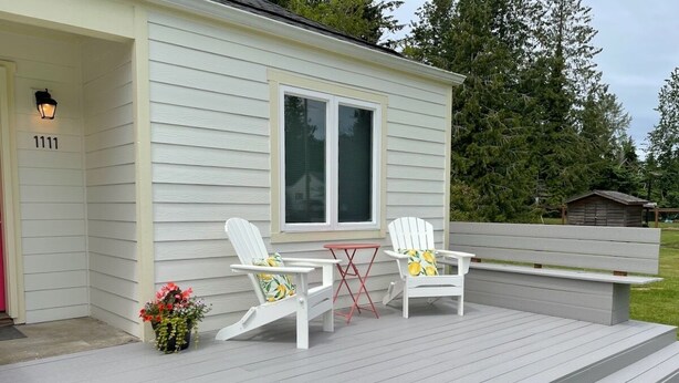 A house with a porch, two Adirondack chairs, a small table, and a flower pot. - Cottage of Tranquility (Bellingham)