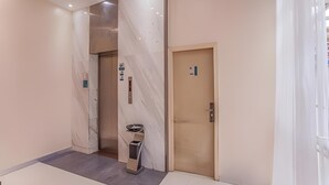 A modern hotel lobby with a marble wall, a reception desk, and an elevator. - City Comfort Inn (Liuzhou)