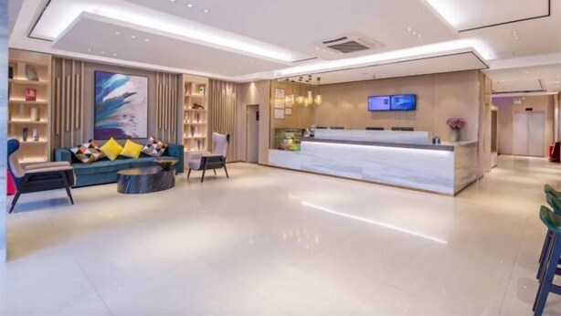 A modern hotel lobby with a reception desk, seating area, and a large abstract painting. - City Comfort Inn (Liuzhou)