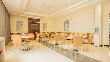 A modern dining area with multiple tables and chairs, a central aisle, and a water dispenser.