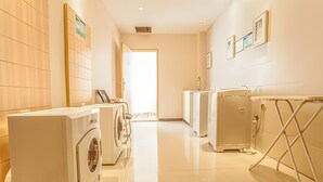 A laundry room with washers and dryers, a wheelchair-accessible shower, and a view of the hallway. - City Comfort Inn (Liuzhou)