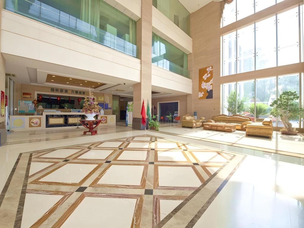 A spacious lobby with a geometric patterned floor, a reception desk, and seating areas.