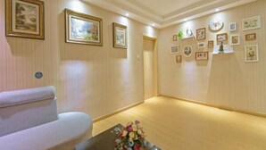 Un hall d'hotel amb un sofà, una taula de café de vidre amb un arranjament floral i quadres amb marcs a les parets.