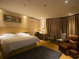 A hotel room with a bed, desk, chair, and a small sofa.