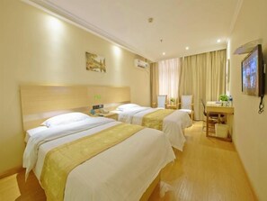 A hotel room with two beds, a desk, and a television.