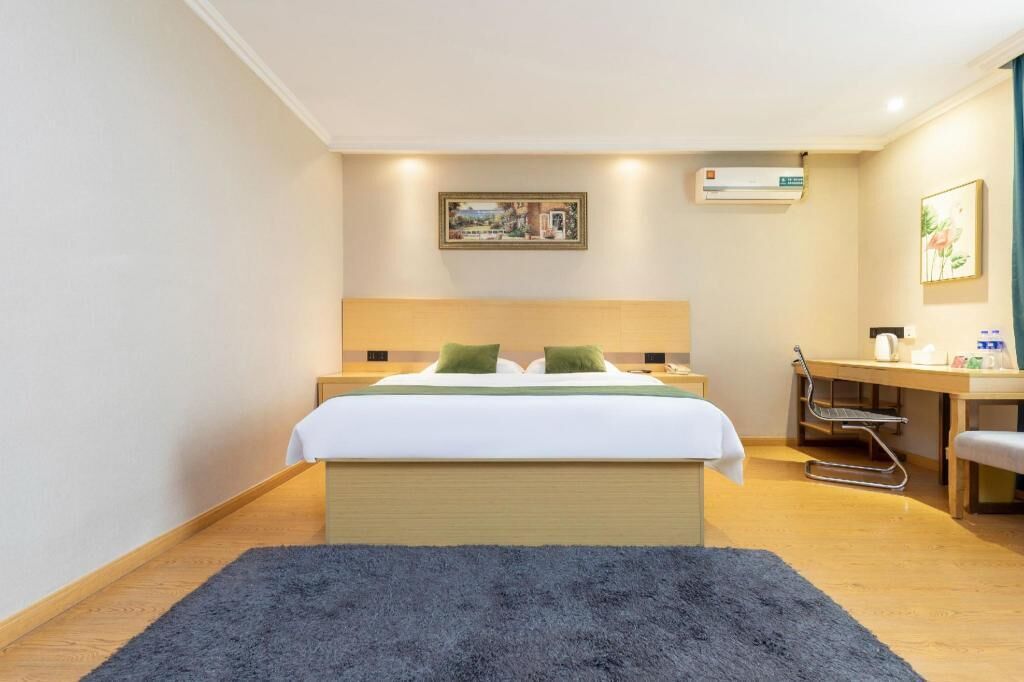 Une chambre d’hôtel équipée d’un lit, d’une table de chevet, d’un bureau, d’une chaise et d’un appareil de climatisation.