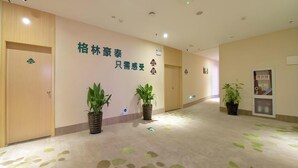 Un passadís d'hotel amb terra clara, plantes en testos i una paret amb caràcters xinesos.